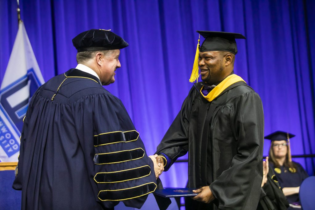 Masters degree graduate shaking the hand of President Kent MacDonald